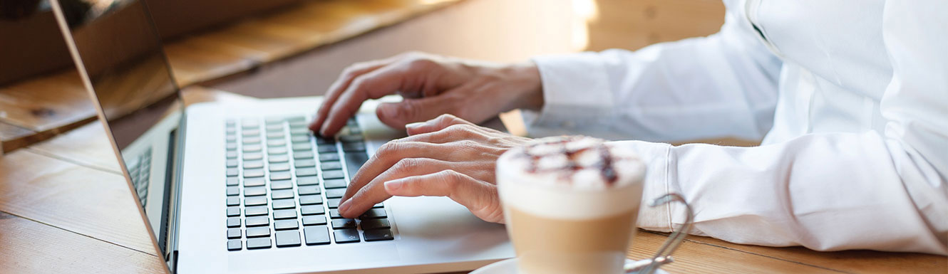 hands typing on laptop with latte